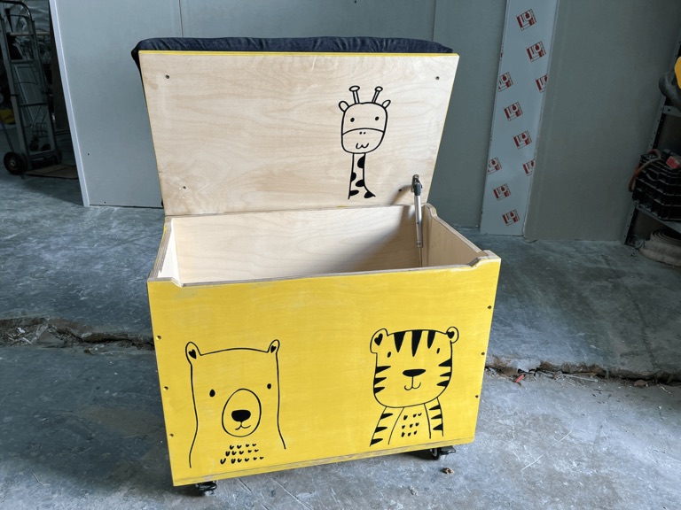 A yellow toy box with animal drawings